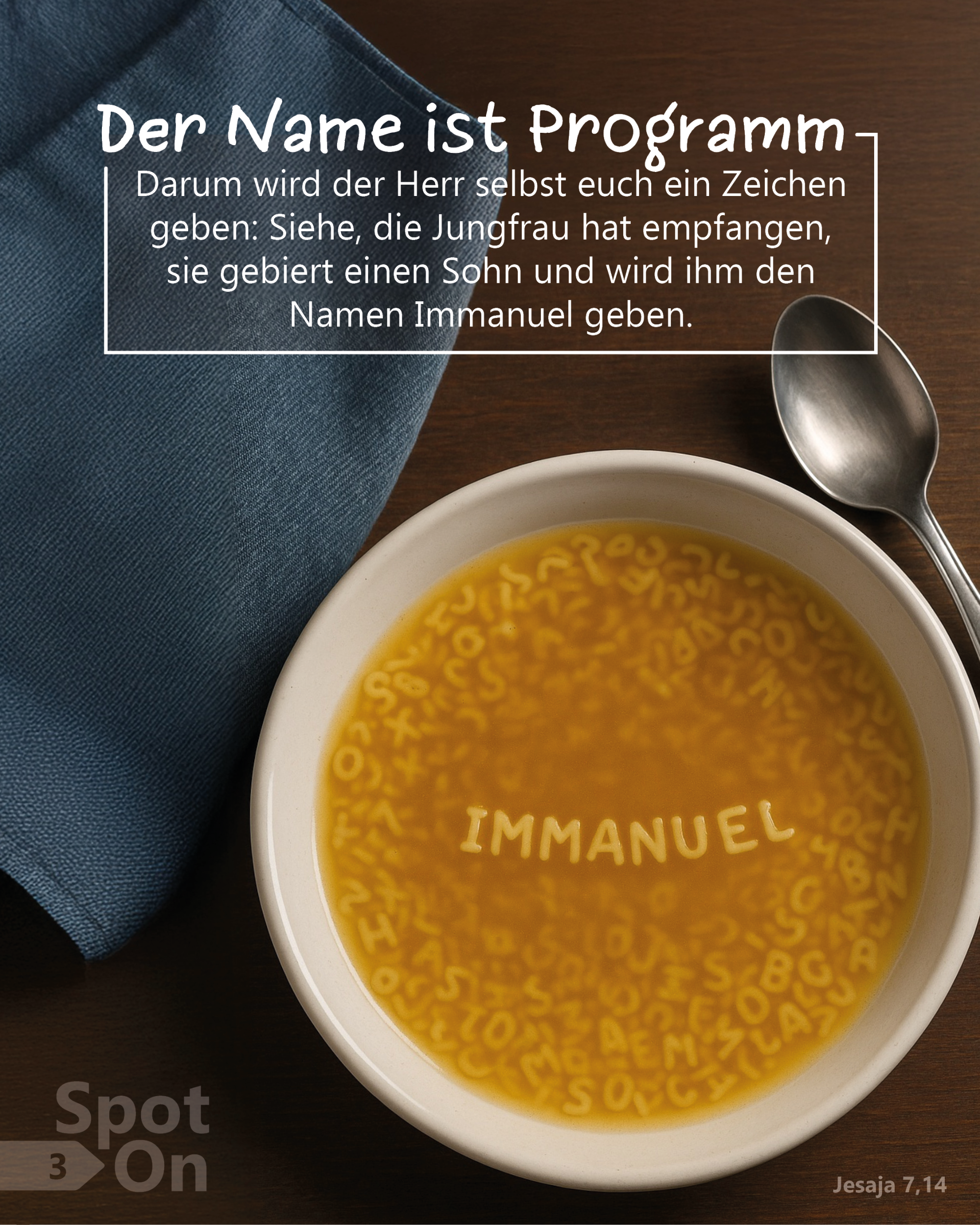 Auf einem dunklen Holztisch steht ein heller Suppenteller, gefüllt mit Buchstabensuppe. In der Mitte bilden die Nudeln gut lesbar das Wort ‚IMMANUEL‘. Rechts neben dem Teller liegen ein Löffel und eine Serviette, links oben liegt ein zusammengefaltetes, blaues Tuch. Im oberen Bildteil befindet sich ein Textkasten mit der Überschrift ‚Der Name ist Programm‘ und dem Bibelvers: ‚Darum wird der Herr selbst euch ein Zeichen geben: Siehe, die Jungfrau hat empfangen, sie gebiert einen Sohn und wird ihm den Namen Immanuel geben.‘ (Jesaja 7,14)